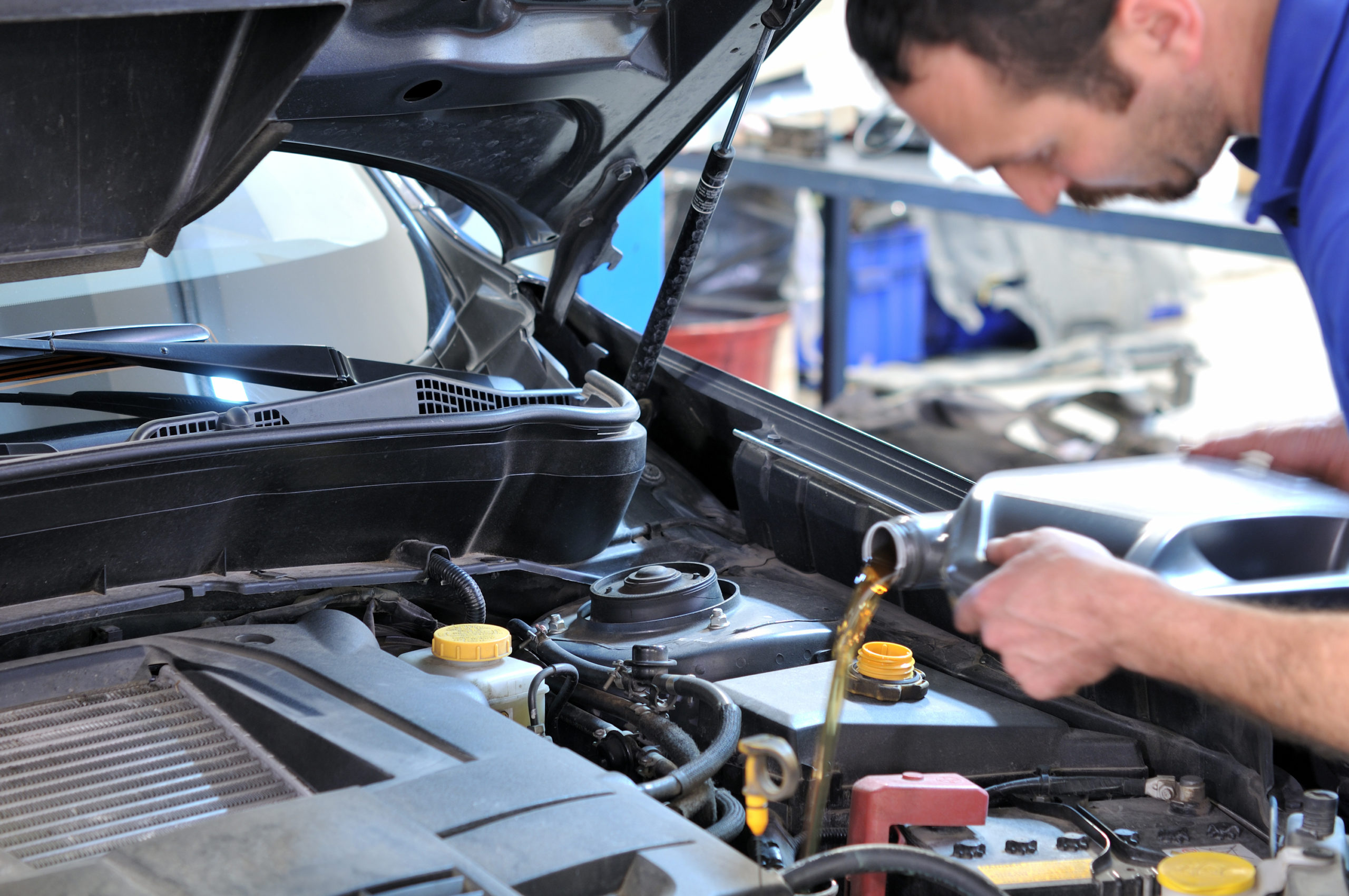 Car mechanic changing oil - model and oil motion blurred.